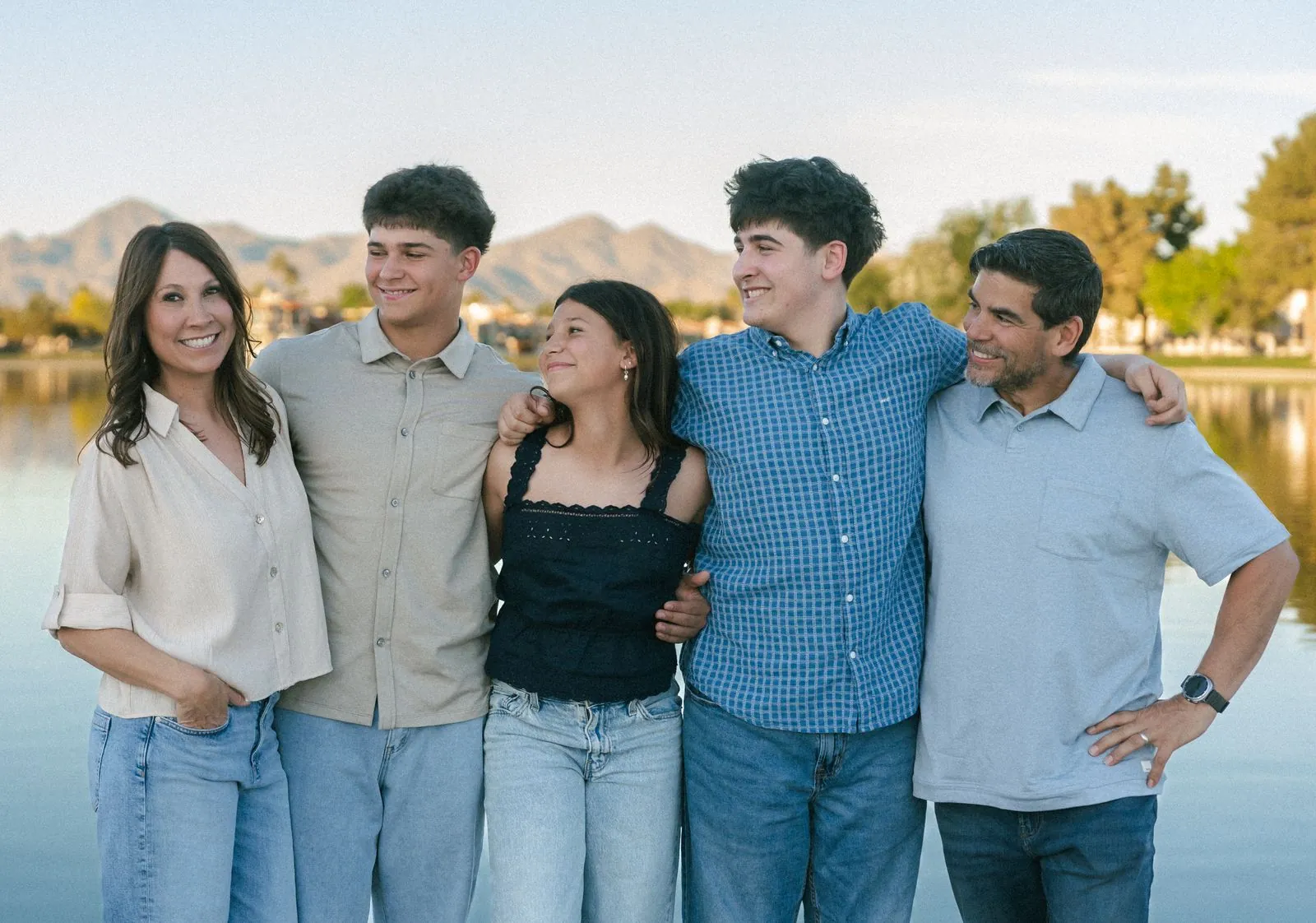 Family of five smiling at each other by a lake at sunset in Scottsdale